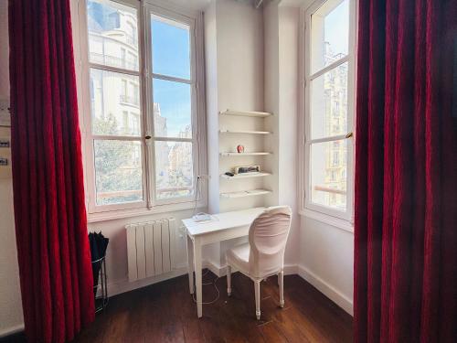 une table et une chaise blanches dans une chambre avec fenêtres dans l'établissement Dream Dwell Paris-Spacious loft in the Marais, à Paris