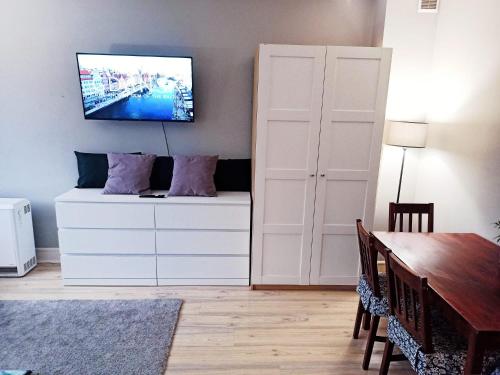 a dining room with a tv on a wall at Brick Lane Apartment in Gdańsk