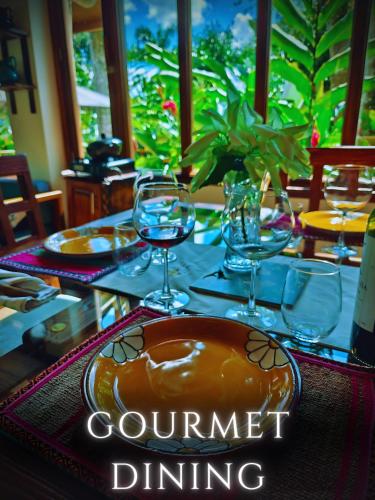 a table with wine glasses and a plate on it at The River House - Upscale Lodge in Puerto Quito