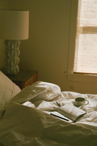 an unmade bed with a cup and a book and a coffee mug at Pamlico Station Edgecamp in Rodanthe