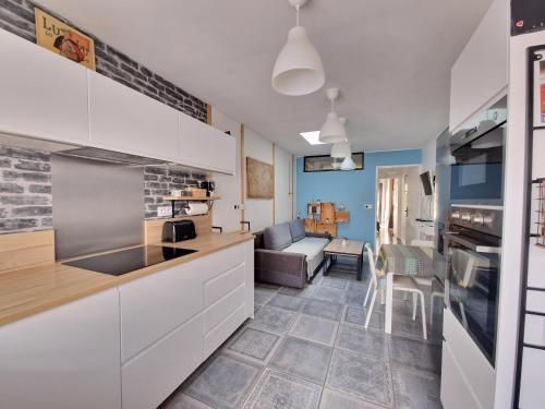 une cuisine avec des armoires blanches et un salon dans l'établissement GAEDREHOME, à Thouaré-sur-Loire