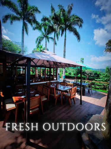 a restaurant with tables and chairs and palm trees at The River House - Upscale Lodge in Puerto Quito