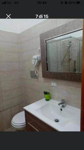 Un baño con lavabo, inodoro y espejo. en Casa Lella, en Policoro
