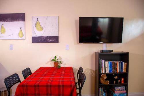 a dining room with a red table with chairs and a tv at Calm, cozy, urban, family-friendly stay in Vancouver