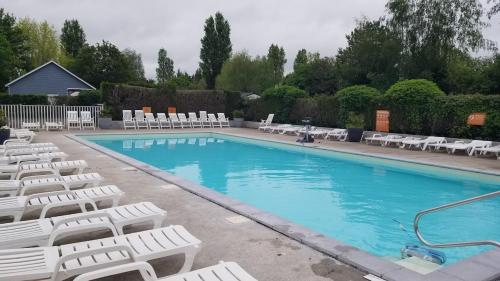 a large swimming pool with white lounge chairs at Mobile home 6P XL Climatisation TV WIFI parcelle XXL au calme in Ivry-la-Bataille