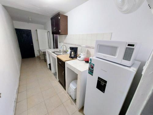 a kitchen with a microwave on top of a refrigerator at Departamento 1 cerca del CAS y consulado,CRIT,Centro de Gobierno y Galerías Mall Cómodo, moderno y con entrada autónoma in Hermosillo