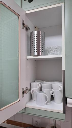 ein Regal mit Tassen und einem Spiegel im Bad in der Unterkunft Apartamentos Maria Cristina con parking gratis in Córdoba