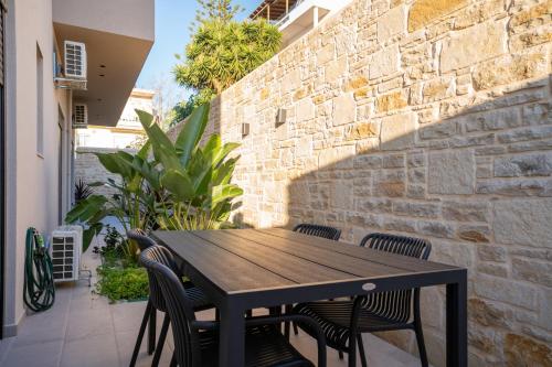 a black table and chairs on a patio with a stone wall at Dreta Suites in Chania Town