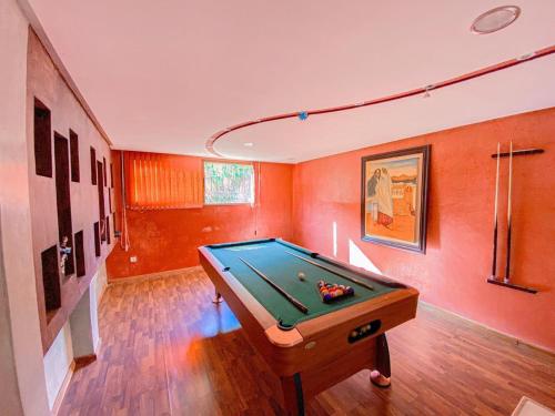 a pool table in a room with orange walls at Amlkis golf royal in Marrakech
