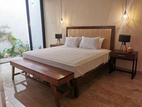 a bedroom with a large bed with two tables and two lamps at Casa Cardenales in Mérida
