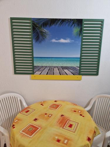 a table with a view of the beach from a window at Gwada paradise, marina du gosier in Le Gosier