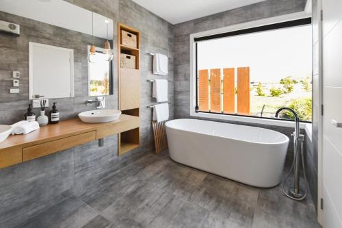 a bathroom with a tub and two sinks and a window at Majestic Mountain Retreat in Twizel
