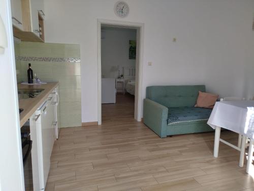 a living room with a blue couch and a kitchen at Cute apartment Arba in Rab
