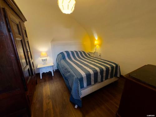 a bedroom with a bed with a striped blanket and two tables at Maison de maître en pierre de 1831 avec vue sur la mer à Porticcio in Porticcio