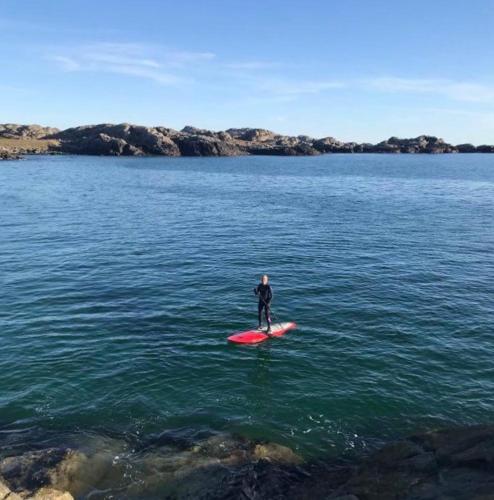 a man standing on a red surfboard in the water at Vestre Karmøyveg 845 in Karmøy