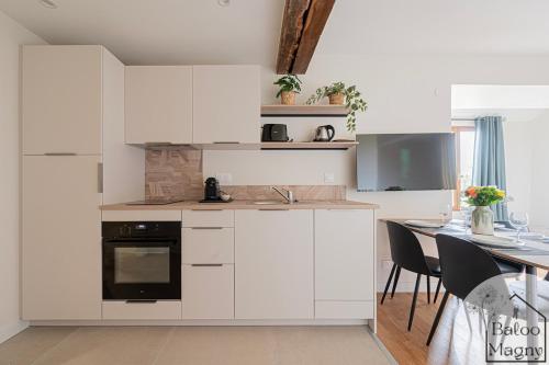 une cuisine avec des armoires blanches et une table avec des chaises dans l'établissement Le Refuge de Bagheera à Disneyland, à Magny-le-Hongre