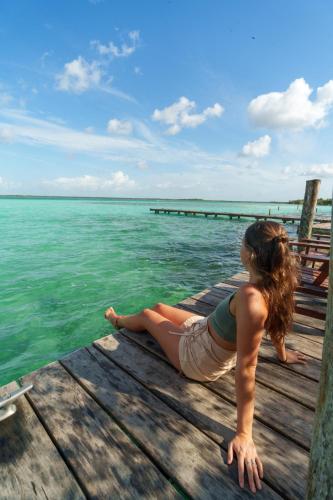 a woman laying on a dock near the water at Azulea Bacalar Hotel & Spa - Lagoon Front in Bacalar