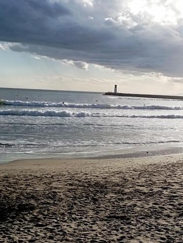 une plage de sable avec un phare dans l'océan dans l'établissement Baddha Konasana, à Agde