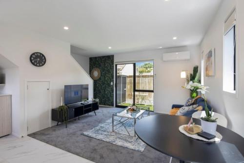 un salon avec une table et un canapé dans l'établissement The Comfortable Biddle Cottage, à Lower Hutt