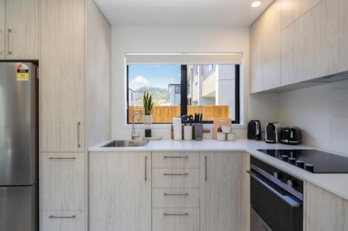 une cuisine blanche avec un évier et une fenêtre dans l'établissement The Comfortable Biddle Cottage, à Lower Hutt