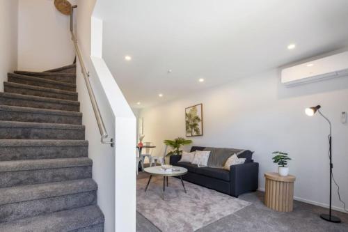 a living room with stairs and a blue couch at Ariki Artistry Lower Hutt 2BR Sanctuary in Lower Hutt
