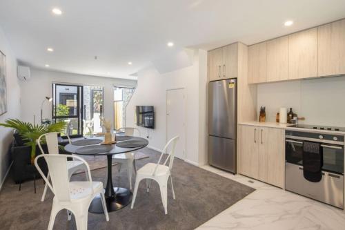 a kitchen with a black table and white chairs at Ariki Artistry Lower Hutt 2BR Sanctuary in Lower Hutt