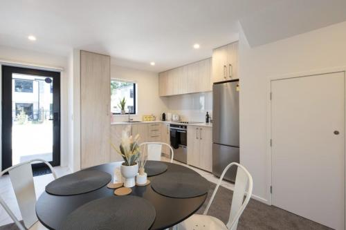 a kitchen with a black table and white chairs at Ariki Serenade House 2BR Peaceful Stay in Lower Hutt