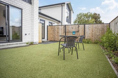 a patio with two chairs and a table on grass at Hillview Hideaway 2-BR Serenity in Upper Hutt