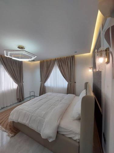 a bedroom with a large bed and two windows at Exquisite 1&2 Bedroom Apartment- Holi Flats Airport Residential Area in Accra