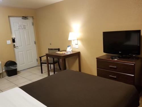a hotel room with a bed and a television and a desk at Suburban Studios Alamogordo in Alamogordo