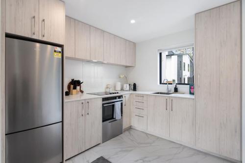 a kitchen with wooden cabinets and a stainless steel refrigerator at Tranquil Stay at Rainey Grove in Lower Hutt