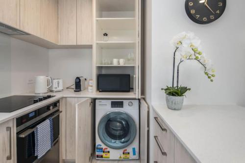 a kitchen with a washing machine and a clock at Sunny 2 BR Oasis in Trentham in Upper Hutt