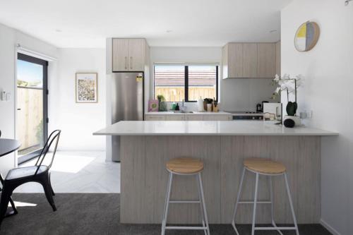 a kitchen with two bar stools and a counter top at Homely Haven in Trentham - 2BR in Upper Hutt