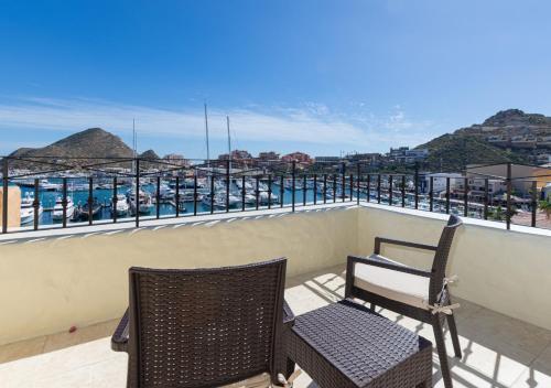a balcony with two chairs and a view of the ocean at Hotel Tesoro Los Cabos in Cabo San Lucas