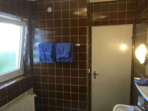 ein Bad mit blauen Handtüchern, die an einer gefliesten Wand hängen in der Unterkunft Appartement Zahn in Bad Waldsee