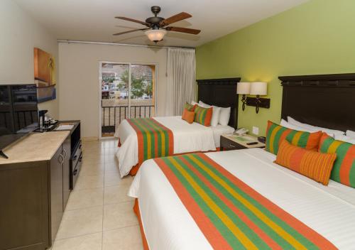 a hotel room with two beds and a television at Hotel Tesoro Los Cabos in Cabo San Lucas