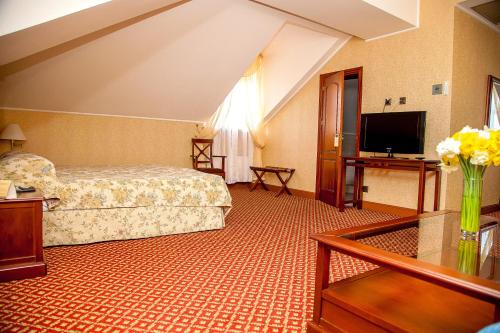 a hotel room with a bed and a flat screen tv at Optima Collection Kamianets-Podilskyi in Kamianets-Podilskyi
