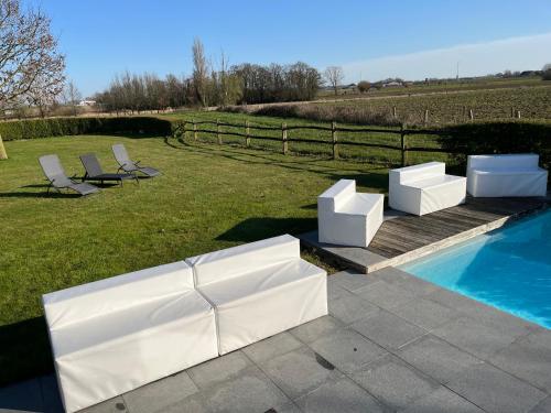 two white chairs sitting next to a swimming pool at Maison mystique in Staden