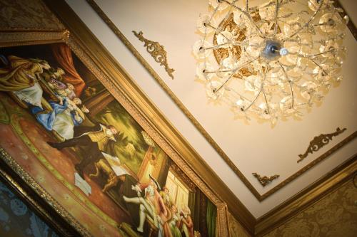 a chandelier on the ceiling of a room with a painting at Chateau Connellsville Art Deco Suite in Connellsville
