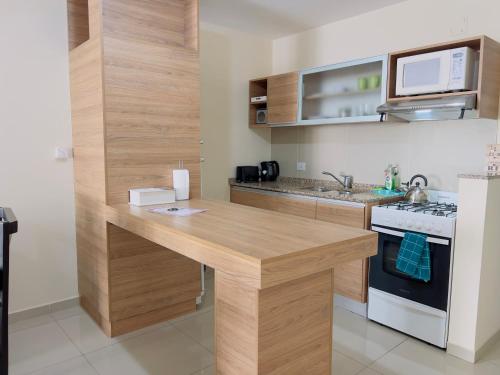 a kitchen with a wooden counter top and a stove at VOW Departamento CÉNTRICO CON COCHERA in Villa Carlos Paz