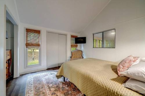 a bedroom with a bed and a chair and windows at Secluded Retreat w Hot Tub, FirePit & Pool Access in Hedgesville