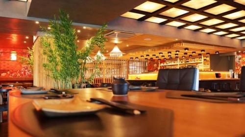 a restaurant with a large wooden table and a bar at Tauá Hotel & Convention Caeté in Caeté