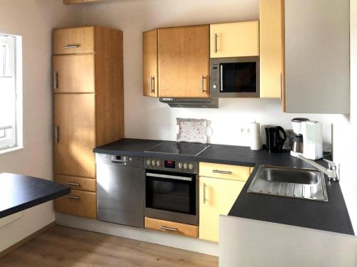 ElsterheideにあるFerienhaus am Partwitzer See, Elsterheideのキッチン(ステンレス製の電化製品、木製キャビネット付)
