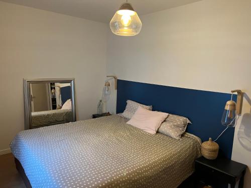 - une chambre avec un lit doté d'une tête de lit bleue et d'un miroir dans l'établissement Jolie maison proche du centre Bordeaux, à Bordeaux