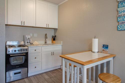 a kitchen with white cabinets and a stove and a table at Executive Keys Condominiums on the Beach in Port Aransas