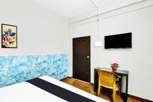 a bedroom with a desk and a bed and a tv at Hotel O Azhar lodge in Calicut