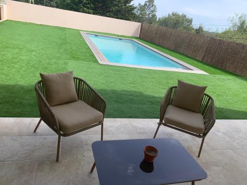 2 chaises, une table et une piscine dans l'établissement Villa entre Vignes et Garrigues, à Assignan