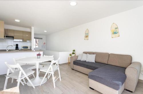 Una sala de estar con un sofá y una mesa y una cocina. en Atardecer 1, en Puerto de Santiago