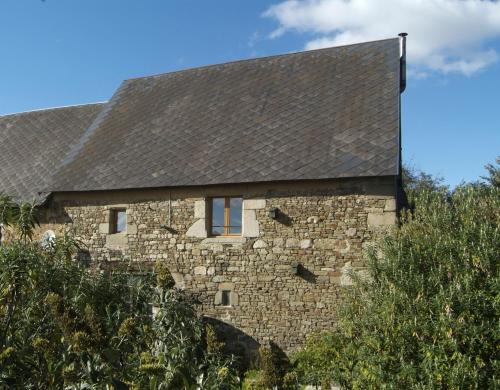 a stone building with a black roof at Le Calipel in Saint-Vigor-des-Monts