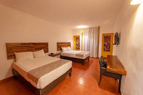 a hotel room with two beds and a desk at Hotel Santa Cruz Huatulco in Santa Cruz Huatulco